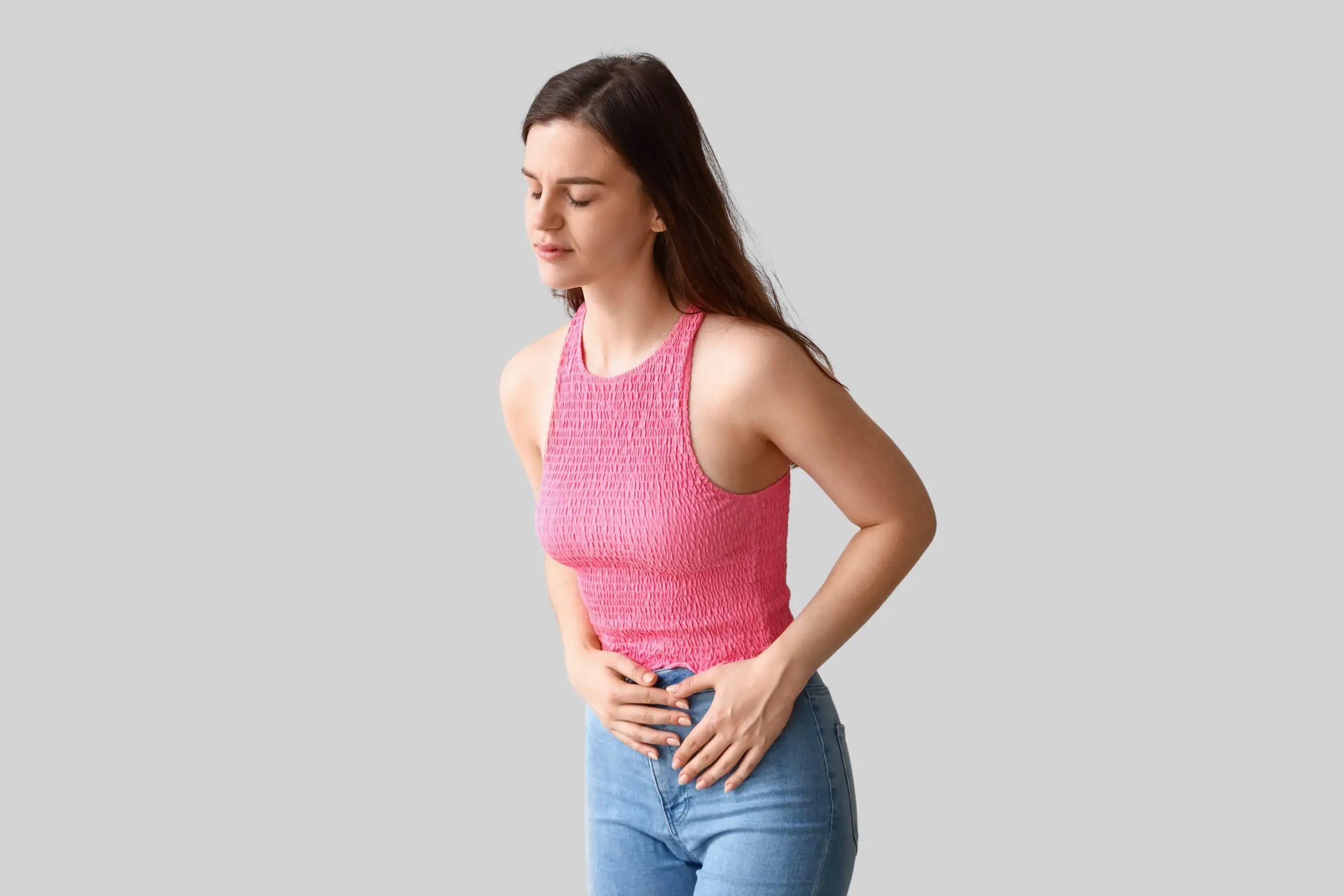 Young woman having menstrual cramps on light background