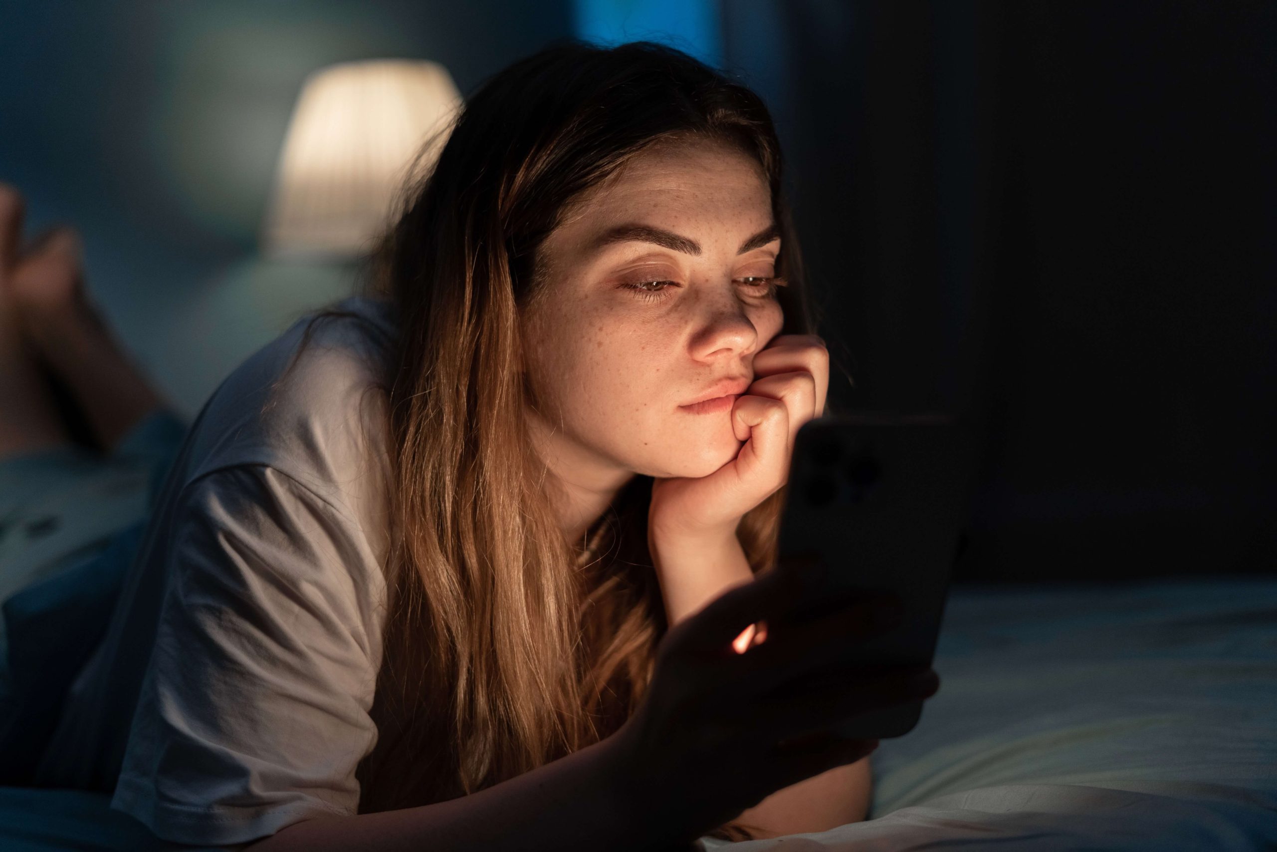 young girl using cell phone Young female checking her cell phone in the dark with pregnancy concerns—she is contemplating how to calculate her due date